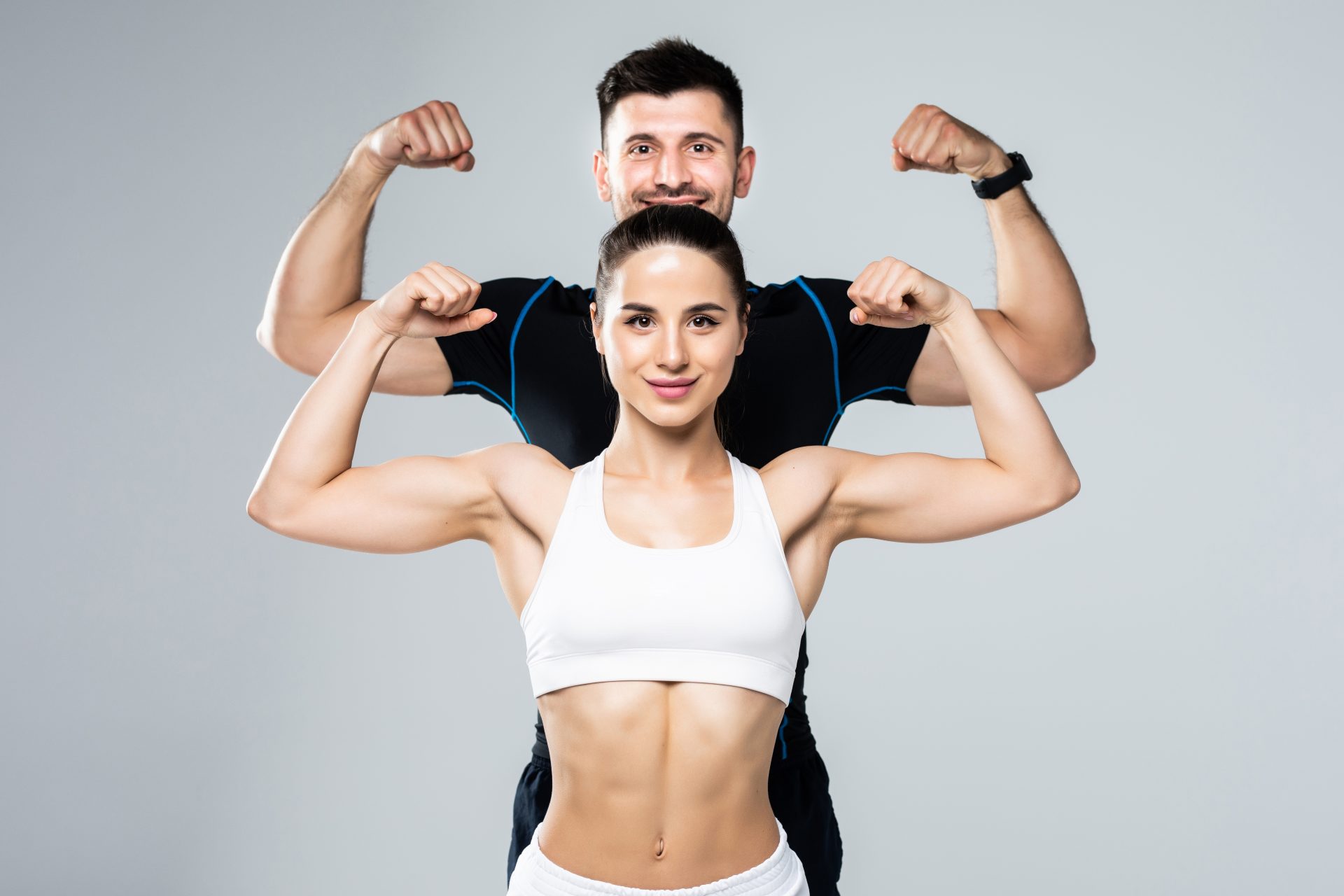 lindo-casal-atletico-mostra-biceps-em-fundo-cinza-foto-premium